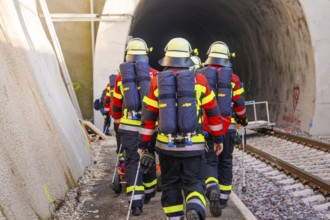Group of firefighters wearing protective clothing enter a dark tunnel, fire brigade exercise on the