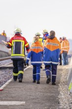 People wearing fire uniforms walk along a railway line, fire brigade exercise at the Hermann Hesse