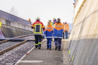 Firefighters in uniforms walk along railroad tracks, sunny background, fire brigade exercise on the