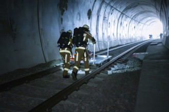 Firefighters move along the rails in the tunnel with equipment, fire brigade exercise on the