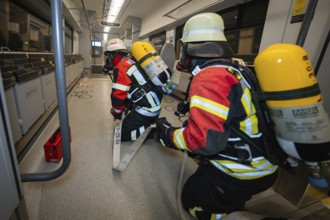 Firefighters move through a train with hoses, fire brigade exercise on the Hermann Hesse railway,