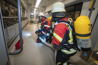 Firefighters inspect the interior of a train in full gear, fire brigade exercise on the Hermann