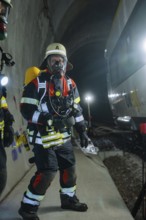 Firefighter standing in a tunnel near a train, equipped for deployment, fire brigade exercise on
