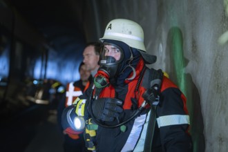 Firefighter wearing respiratory protection in a tunnel surrounded by other rescue workers, fire