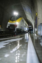 A train in a tunnel surrounded by firefighters on wet ground during rescue work, fire brigade