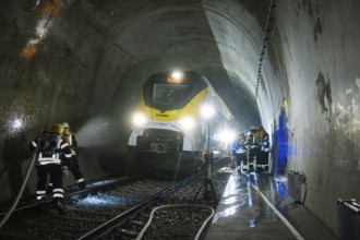 Firefighters during an emergency operation in a dark train tunnel next to a stationary train, fire