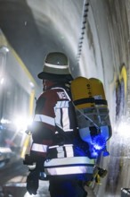 A firefighter with a respirator in an illuminated tunnel during an operation, fire brigade exercise