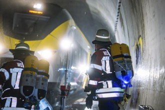 Firefighters wearing respiratory protection against a yellow train in a tunnel, fire brigade