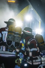 Firefighters wearing respiratory protection in an illuminated tunnel during an operation, fire