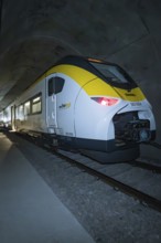 A train with yellow and white colors stands in the tunnel at night, fire department exercise on the