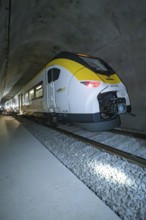 A yellow and white train passes through a tunnel at night, fire department exercise on the Hermann
