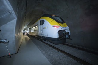 A brightly lit yellow-black train stands in a dark tunnel, fire department exercise on the Hermann