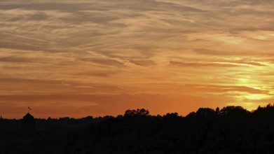 Beautiful sunset with orange sky over silhouettes of trees, Frankenwald nature park Park
