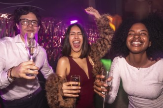 Happy diverse friends clinking champagne in a vibrant nightclub, dancing under dynamic lights and