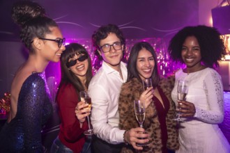 Diverse group of smiling friends celebrating together during a festive event, holding champagne