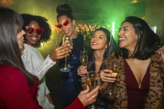 Diverse group of young women friends happily toasting with champagne flutes, celebrating a special