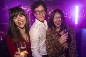 Young friends enjoying a vibrant party atmosphere, smiling and laughing while holding glasses of