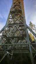 Vertical view of a high metal bridge, old railroad bridge, in front of a bright blue sky,