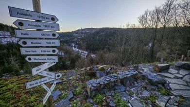 Wooden signpost at a viewpoint with views over wooded hills and valleys in winter, Franconian