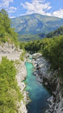 Gorge with clear water and surrounding green mountains under blue sky, Soca Valley, Slovenia