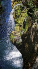 Waterfall runs over moss-covered rocks and splashes into a blue pool, Soca Valley, Slovenia