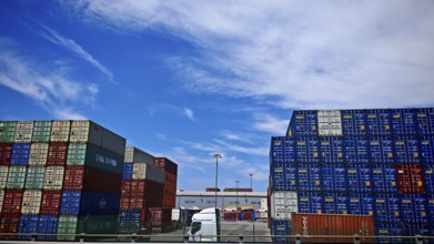Large stacks of colorful containers in logistics warehouse under slightly cloudy sky, Slovenia