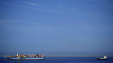Large cargo ship full of containers on open sea with clear blue sky, Slovenia