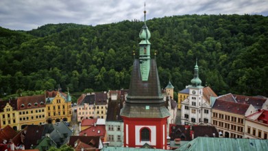 View of a town with church tower and historic buildings in front of a forest, Loket, Czech Republic