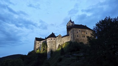 Illuminated castle at dusk against a blue sky, Loket, Czech Republic