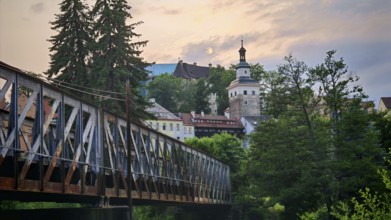 Idyllic city view with old railroad bridge and tower over a river in the evening light, Loket,