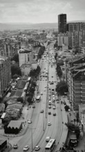 Urban scene with a long busy street lined with tall buildings in black and white, Pristina, Kosovo