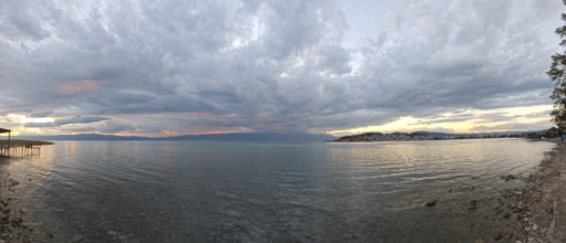Wide panorama of a lake at sunset, with dramatic clouds in the sky, Lake Ohrid, North Macedonia