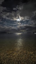 A nighttime lake panorama with reflecting moonlight and dramatic clouds in the sky, Lake Ohrid,