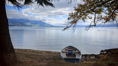 A boat is quietly lying on the shore of a lake with autumn colors, Lake Ohrid, North Macedonia