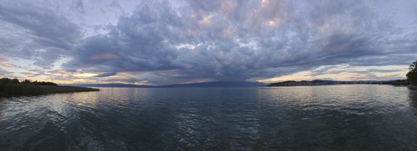 Panoramic view of a lake surrounded by dramatic clouds at sunset, Lake Ohrid, North Macedonia