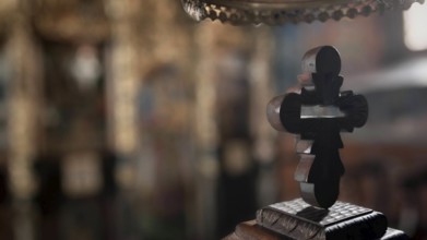 An intricately carved wooden cross against a blurred church background with mystical reflections,