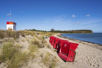 DLRG water rescue, red beach chairs side by side on sandy beach, beach and cliffs, people on the