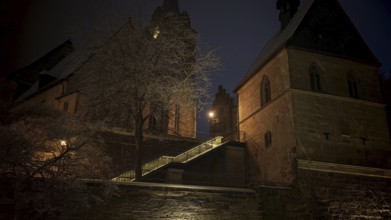 Illuminated church in the dark, surrounded by trees, conveys medieval atmosphere, view of Kronach,