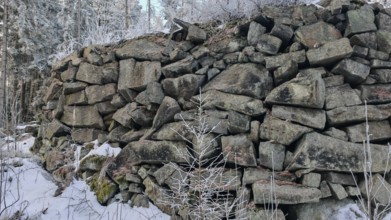 Large stone wall in snowy forest, grey and cold winter landscape, Fichtelgebirge