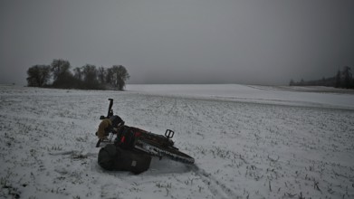 Bicycle lying in the snow on a field with trees in the background under a grey sky, Frankenwald