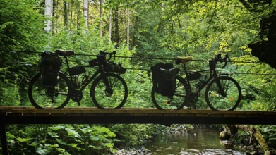Two bikes on a wooden bridge over a river in the middle of a forest, Slovenia
