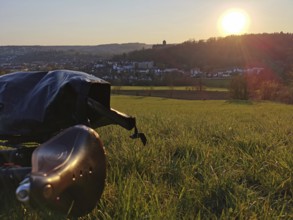 View of a city at sunset from a meadow with a bicycle in the foreground, Upper Franconia