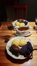Franconian cuisine, a cozy dinner with goose breast, dumplings, red cabbage on a wooden table,
