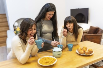 Three young adult women friends enjoying breakfast with muffins, coffee, and cereal, sharing smiles