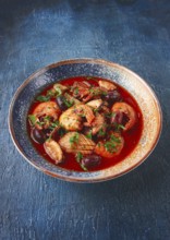 Seafood in tomato sauce with olives, on a dark blue background