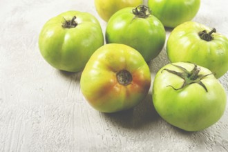 Green tomatoes scattered on the table, unripe tomatoes, raw, selective focus, no people