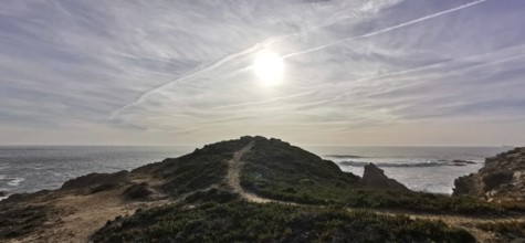 A trail leads over a hill, the sun shines over the coast, Southwest Alentejo nature park Park and