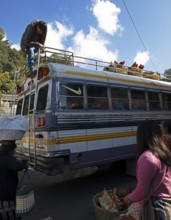 Gualtemalan man packs baskets with chickens on the roof of a bus, market in Sololá, Highlands,