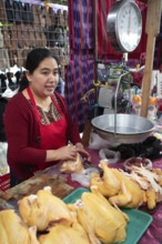 Mayan woman wearing traditional clothing with chicken meat and scales at the market in Sololá,