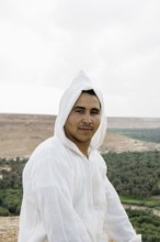 Young man and oasis in the background, near Merzouga, Meknès-Tafilalet region, Erg Chebbi, northern